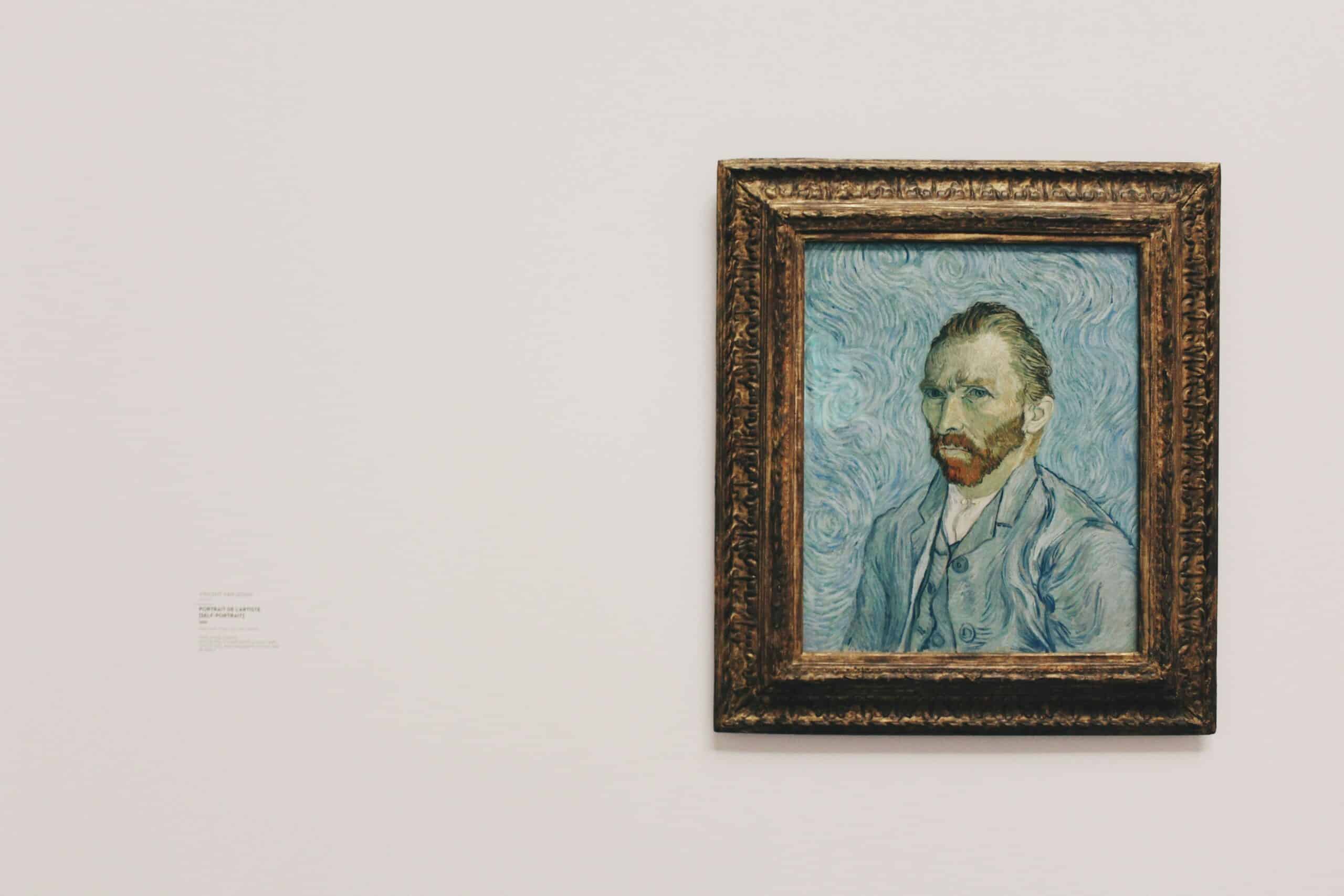 Large framed self-portrait painting by Van Gogh in an ornate gold frame mounted on a pale gallery wall